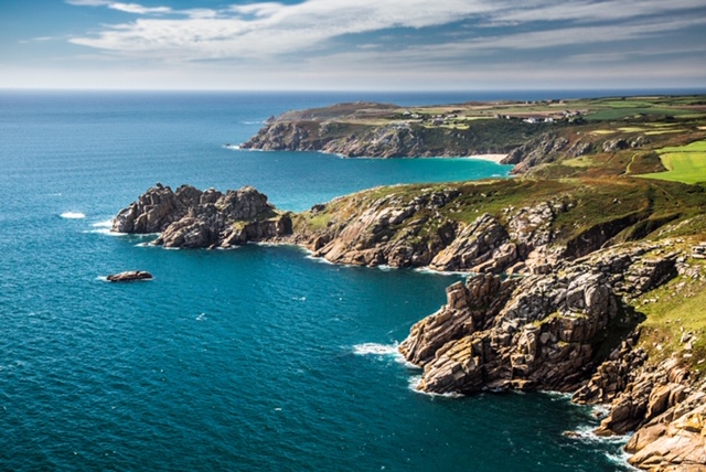 The rugged coastline from above showing The Logan Rock, Porthcurno and The Minack Theatre.