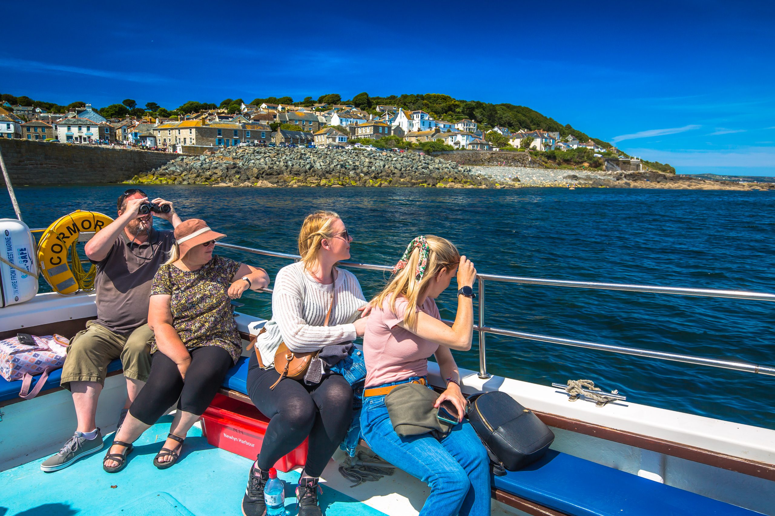 Tourists looking out for wildlife whilst on a coastal cruise from Mousehole in Cornwall.