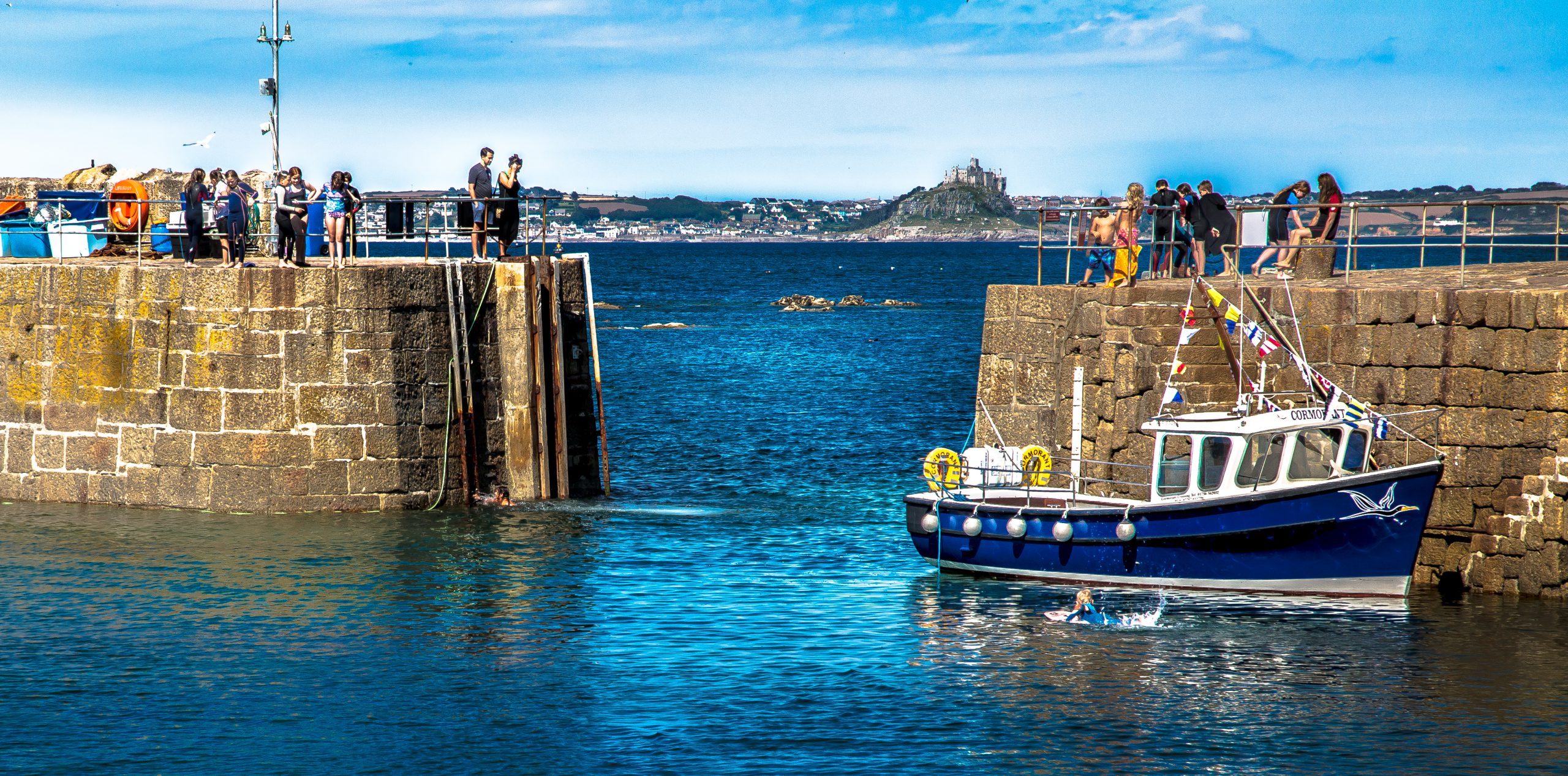 The Cormorant waiting to collect the next group of passengers from the South Pier in Mousehole harbour.